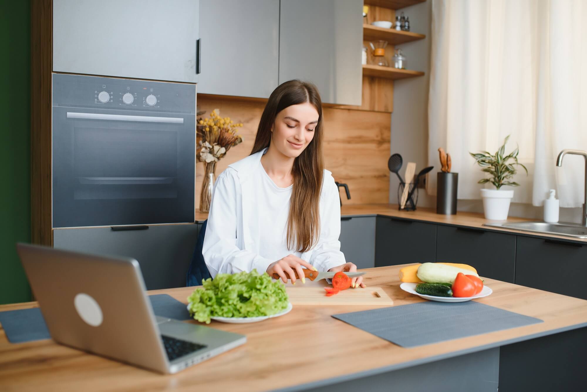 woman blogger nutritionist prepare a salad with fresh vegetables and conducts a video conference