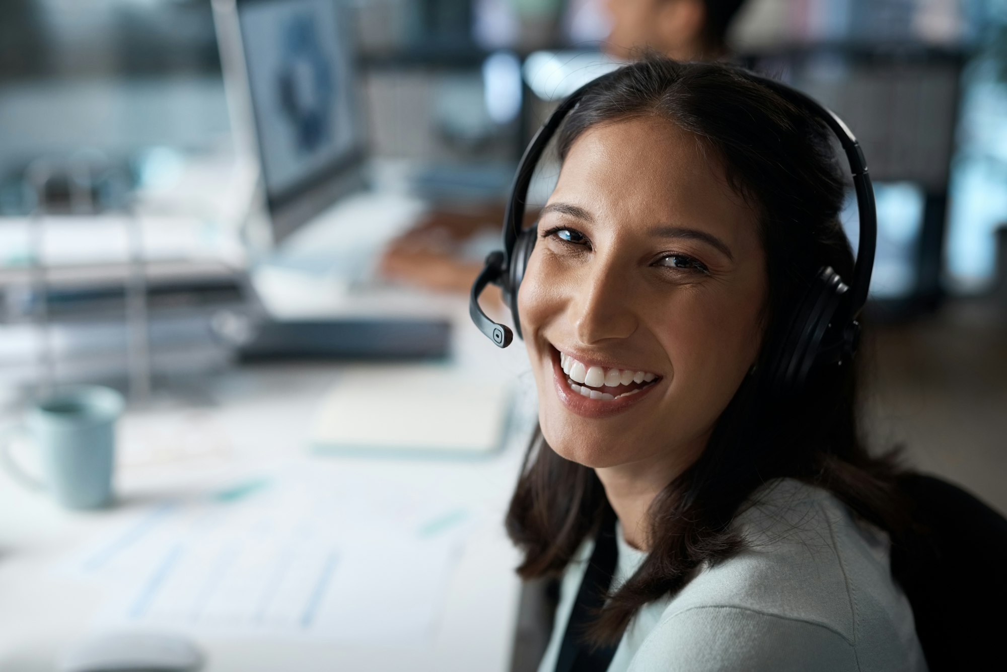 Delighting customers is what we do. Portrait of a young woman using a headset in a modern office.