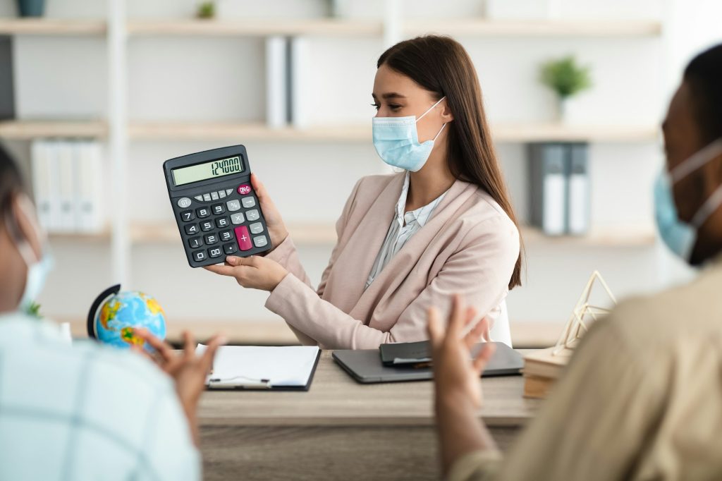 Lady Showing Calculator With Vacation Price To Couple In Office