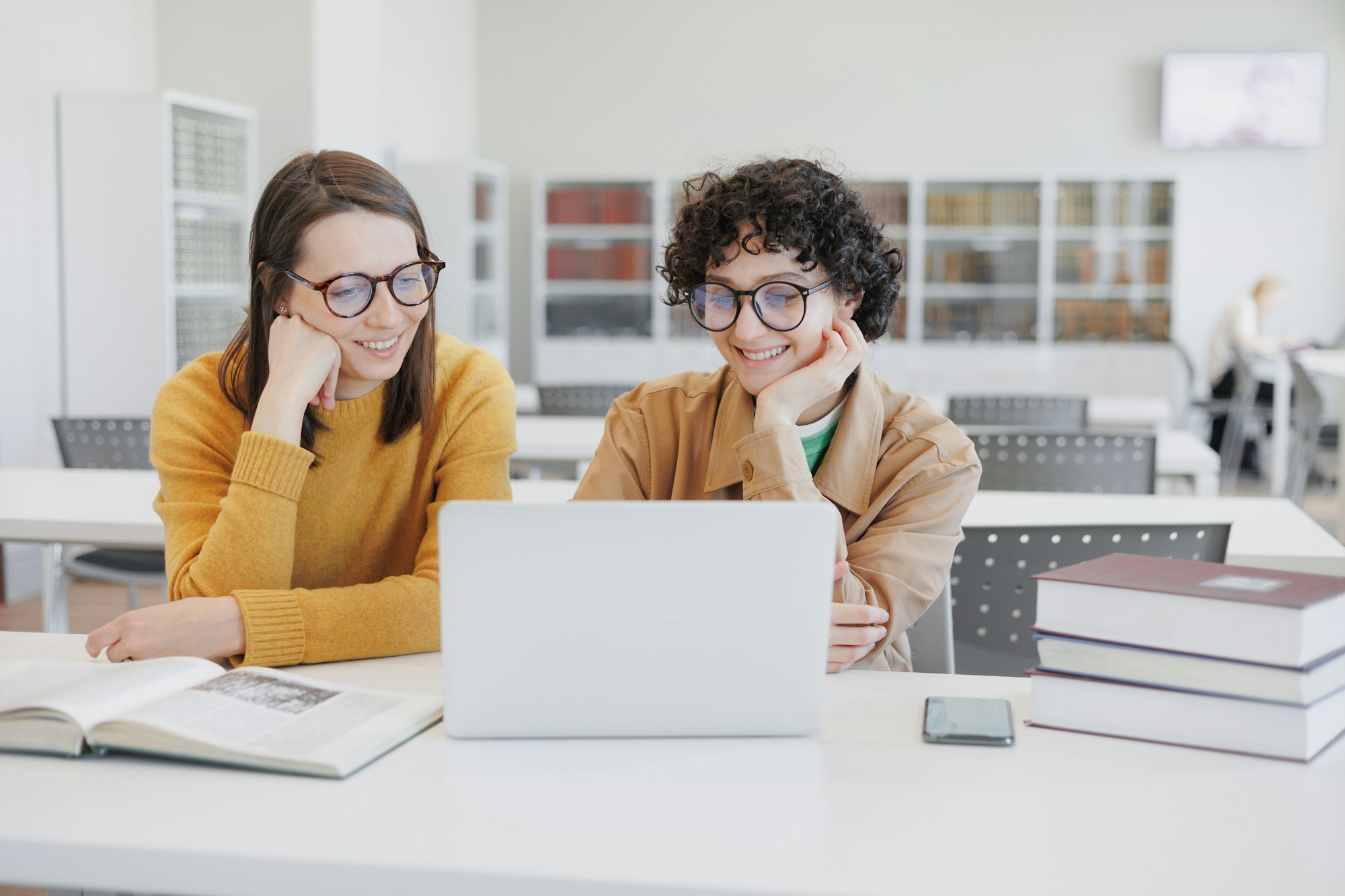 two female colleagues work on laptops in coworking office, library. online training webinar