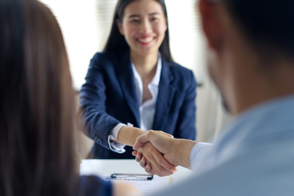 Young Asian business people shaking hands in the office between female and male.